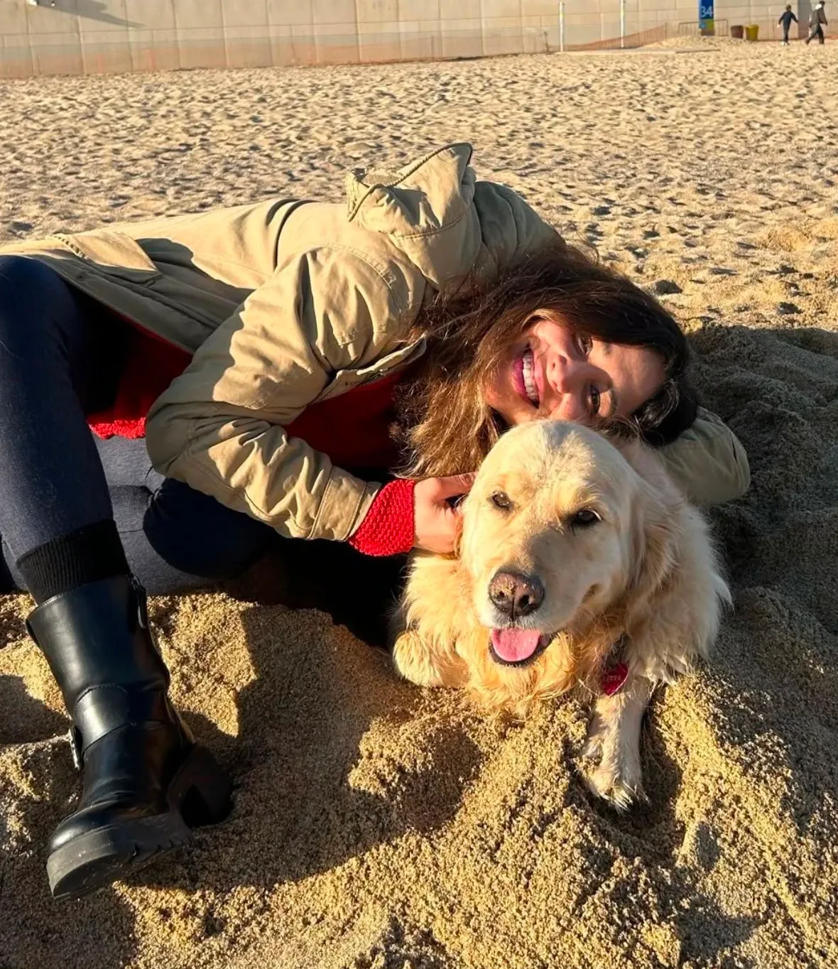 Mariana allongée sur le sable enlaçant un golden retriever sous le soleil d'hiver à Barcelone