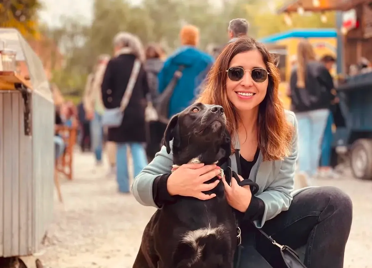 Mariana avec des lunettes de soleil enlaçant un labrador noir dans un marché en plein air à Barcelone